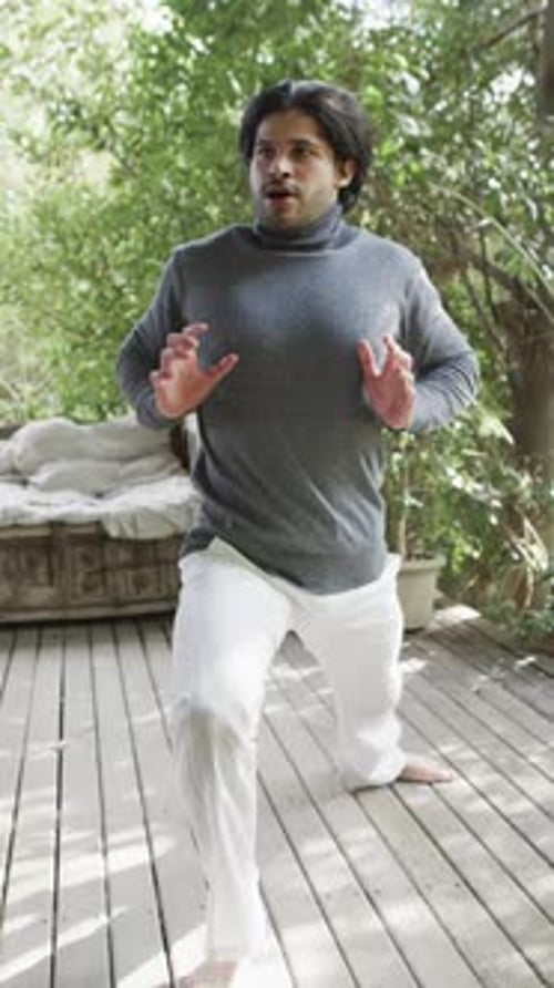 Vertical video of biracial man practicing yoga on terrace in nature, slow motion