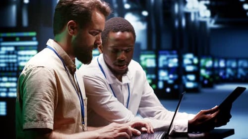 Adults Collaborate on Laptop in Server Room