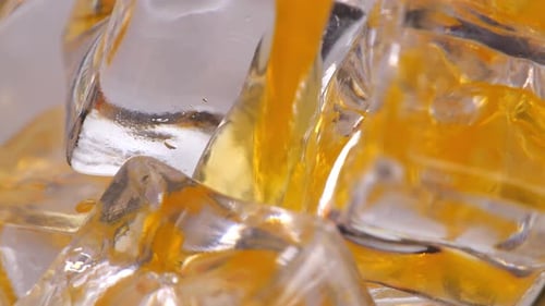 Close Up Of Orange Juice Being Poured Over Ice Cubes