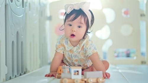 Baby Girl Playing with a Toy Train at Home