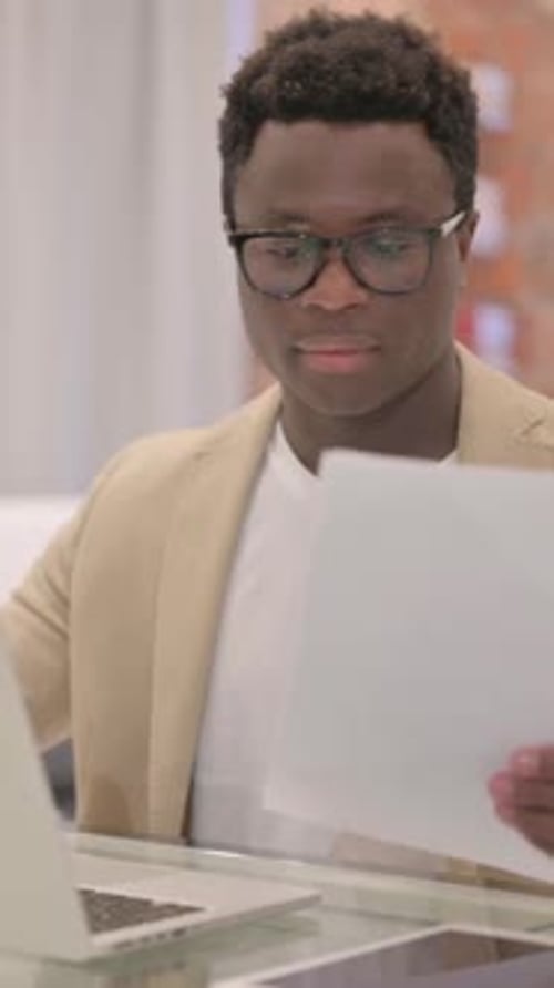 Young Adult Male Reviews Documents at Office Desk