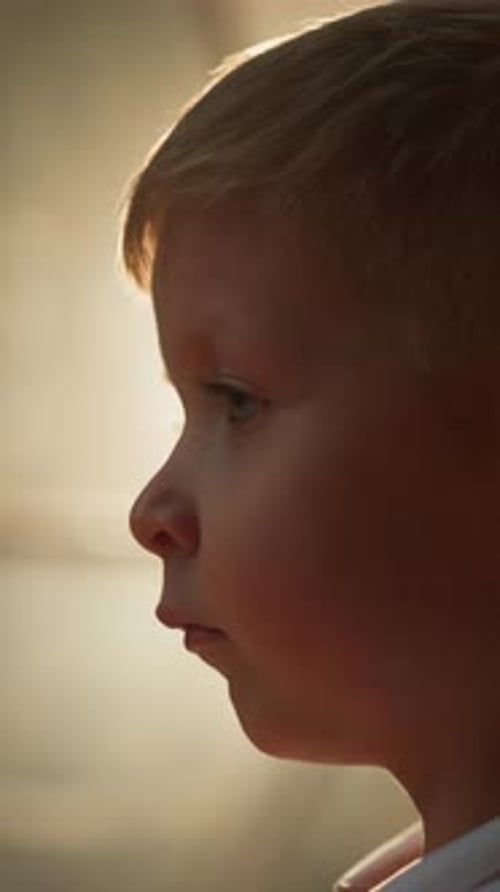 Le petit enfant a l'air calmement debout face à une lumière vive