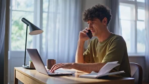 Young Adult Working at Desk and Talking on Phone