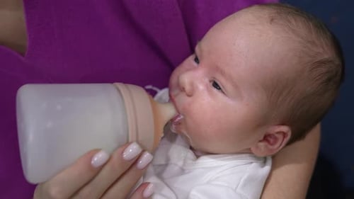 Mother Feeds Bottle to Adorable Infant
