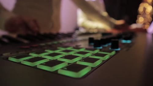 Hands Creating Music on Beat Machine at Night