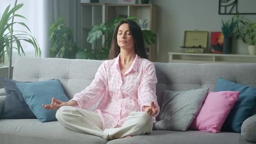 Woman Meditating on Couch in Living Room