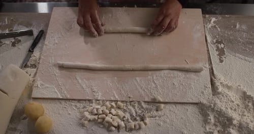 Frau knetet und bereitet Teig für frische handgemachte Gnocchi in der Nudelfabrik zu