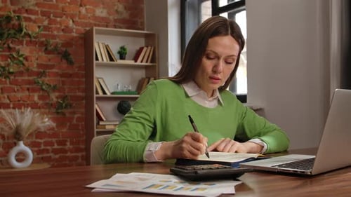 Focused Woman Working on Financial Calculations at Desk