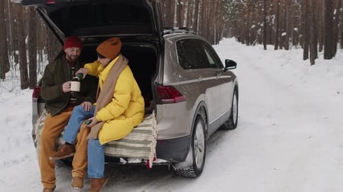 Couple Enjoying Hot Tea in Car Trunk on Winter Day