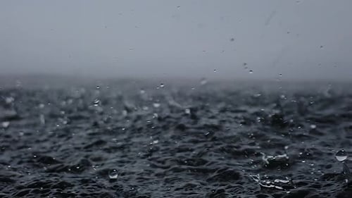 Regen fällt in den endlosen Ozean, ganz nah. Es prallt kurz zurück in die Luft, nachdem es das Meer getroffen hat
