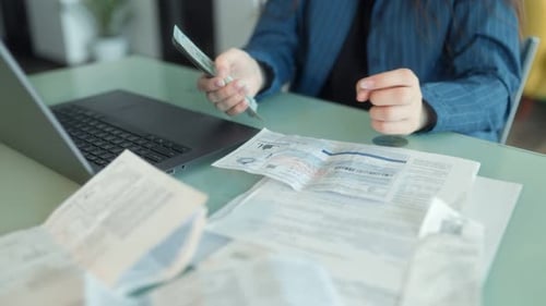 Woman Paying Bills with Cash and Receipts at a Home Office Desk