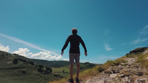 Unrecognizable Guy in Shorts Raises His Hands Up After Conquering the Summit with a Beautiful View