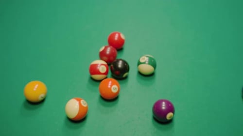 Billardkugeln zerstreuen sich nach einem kräftigen Breakshot auf dem grünen Billardtisch