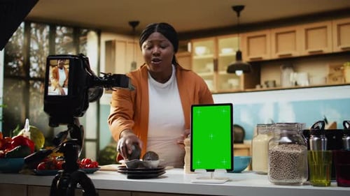 Tableta vertical con pantalla verde, influencer afroamericano filmando un vlog de comida