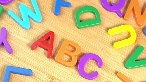 Colorful ABC Alphabet letters rotate on a wooden background. The concept of learning, school