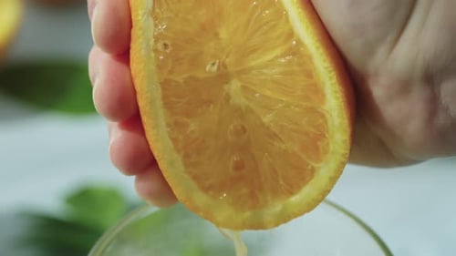 Hand Squeezing Orange Juice Over Glass Close-Up