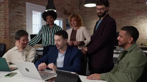 Diverse Colleagues Collaborating on Laptop in Office