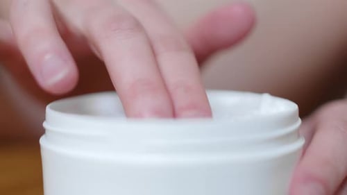 Female Hand Applying Moisturizing Cream. Close Up Shot