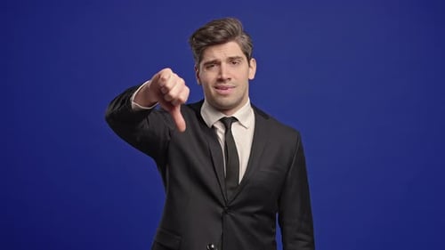 Businessman in Suit Giving Thumbs Down Dislike with Disapproving Look on Blue