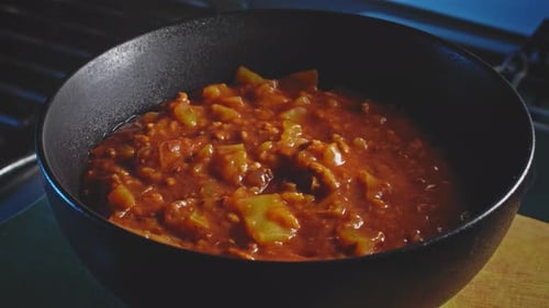 Silver spoon scoops meal from black bowl in preparation for eating soup stew