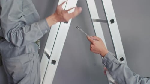 Young Adult Repairing Air Conditioning Unit on Ladder