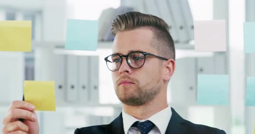 Séquence vidéo 4k d'un jeune homme d'affaires écrivant des notes sur un mur de verre dans un bureau