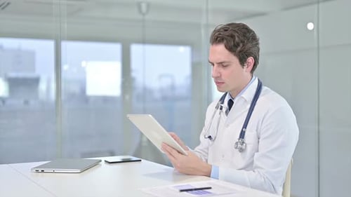 Focused Young Male Doctor using Tablet in Modern Office