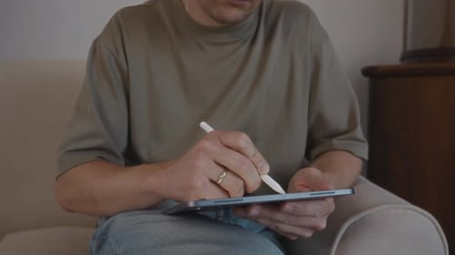 Man Using Stylus on Tablet While Sitting