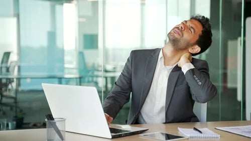 Businessman Massaging Neck at Office Desk