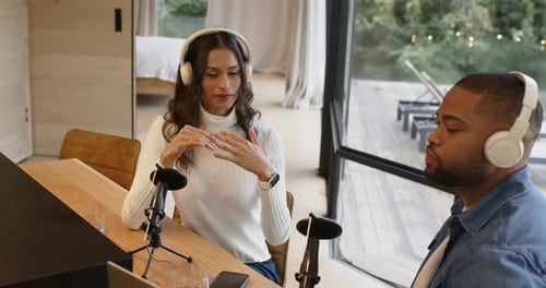 Divers co-animateurs discutent après qu'une femme parle au micro, fait des gestes, sirote de l'eau à la table du studio
