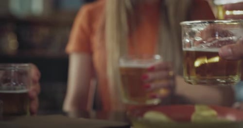 Close Up on Clinking Glasses with Beers Held by Young Friends Celebrating During Day Tim