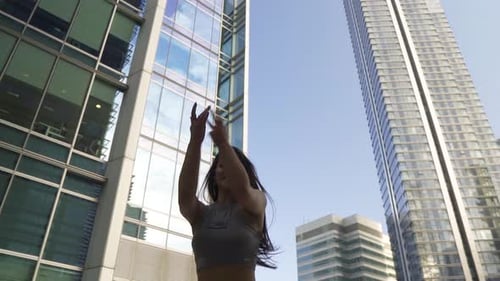 Brown hair gorgeous woman with healthy body performing modern dance moves in a city centre with tall