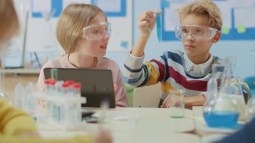 Elementary School Science Classroom: Smart Boy Mixes Chemicals in Beakers and Cute Girl Writes Down