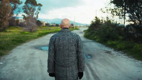 Man Walking on Dirt Road in Rural Area