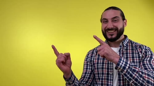 Happy Man Pointing on Yellow Background