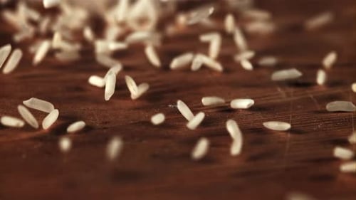 Rice Grains Pouring on Wooden Surface Close Up