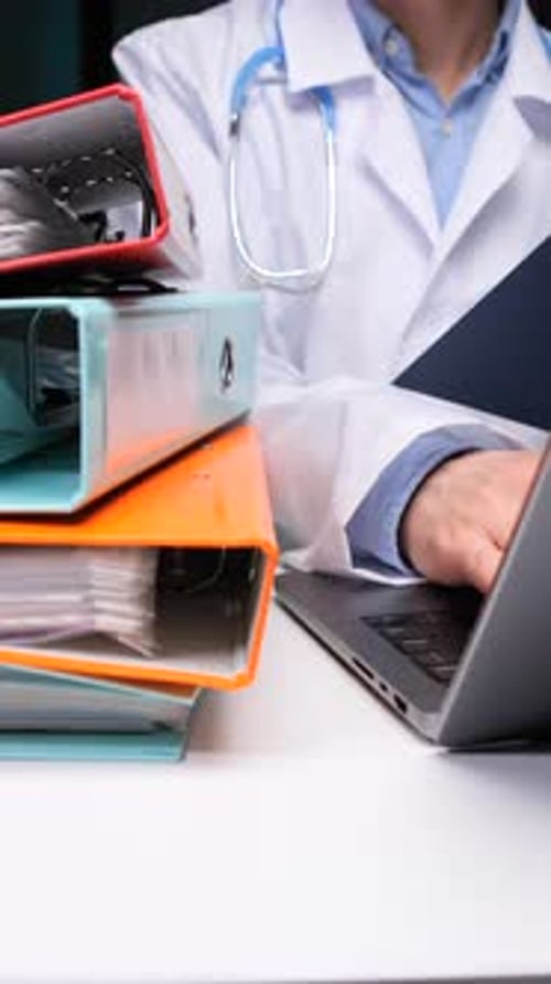 Vidéo verticale : Docteur en blouse médicale traitant les données des patients et les dossiers médicaux à l'aide d'un ordinateur portable
