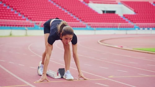 Asiatische junge Sportlerin sprintet auf einer Laufbahn im Freien im Stadion.