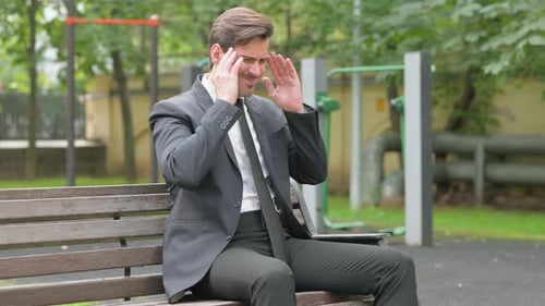 Tense Businessman with Migraine Sitting Outdoor