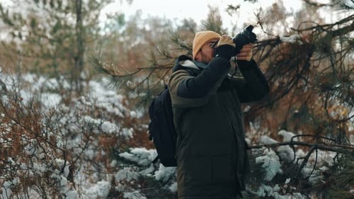 Man Photographs Winter Landscape in Snowy Forest