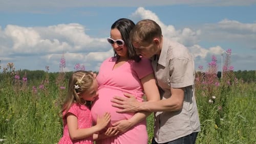 Famille enceinte heureuse avec fille en été