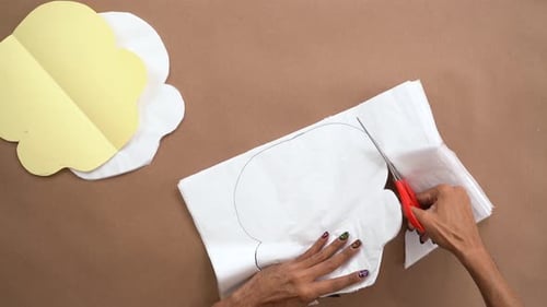 Person Cutting Tissue Paper Cloud Shape with Scissors