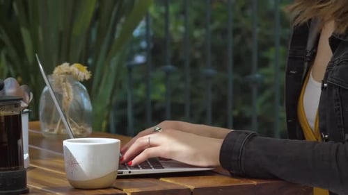 Woman Typing On Her Laptop In A Coffee Shop