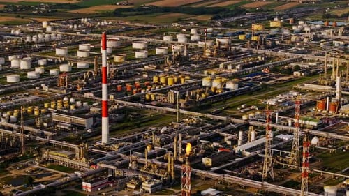 Coucher de soleil d'une raffinerie de pétrole avec réservoirs de stockage et haute cheminée en Europe industrielle