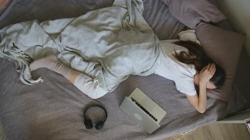 Tired Woman Sleeping on Bed with Laptop