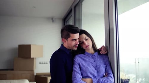 Loving couple hugging by window with cardboard boxes