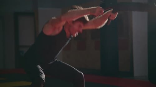 Young Man Trains with Battle Rope in Dimly Lit Gym