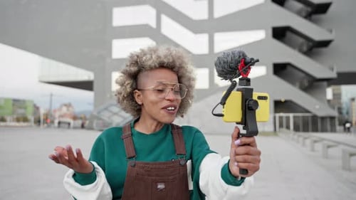 Funny African American Woman Influencer Filming a Video Vlog with Cell Phone in the City for Online