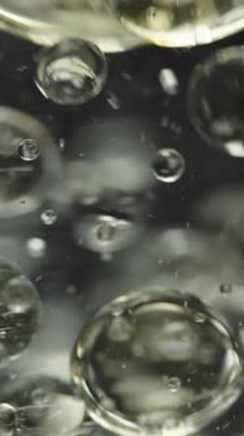 Vertical video. Bubbles in water on a black background, oil in water. Macro, Slow Motion.