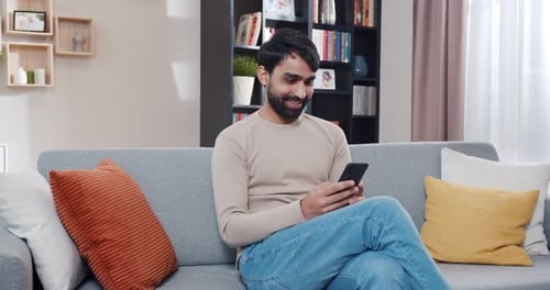 Young Adult Using Mobile Phone on Couch Indoors